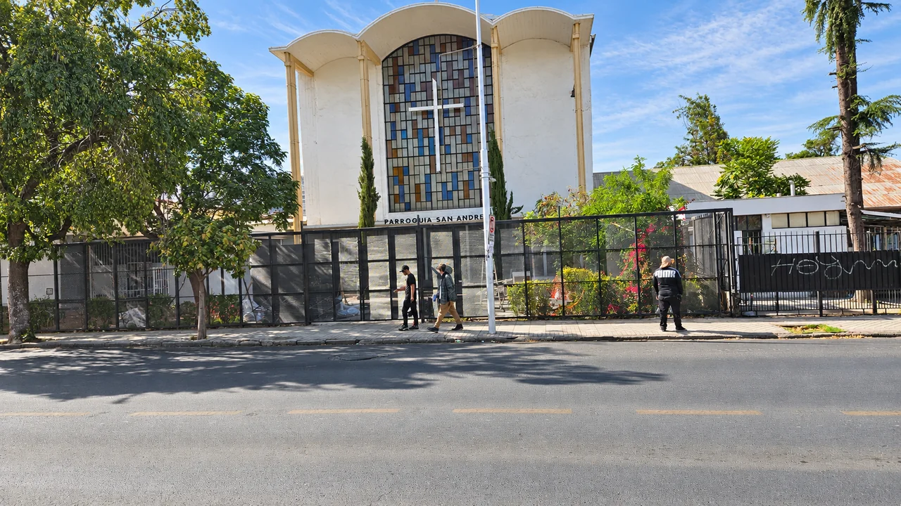 Fachada de la Parroquia San Andrés con su cruz, vitrales y cierre de acceso