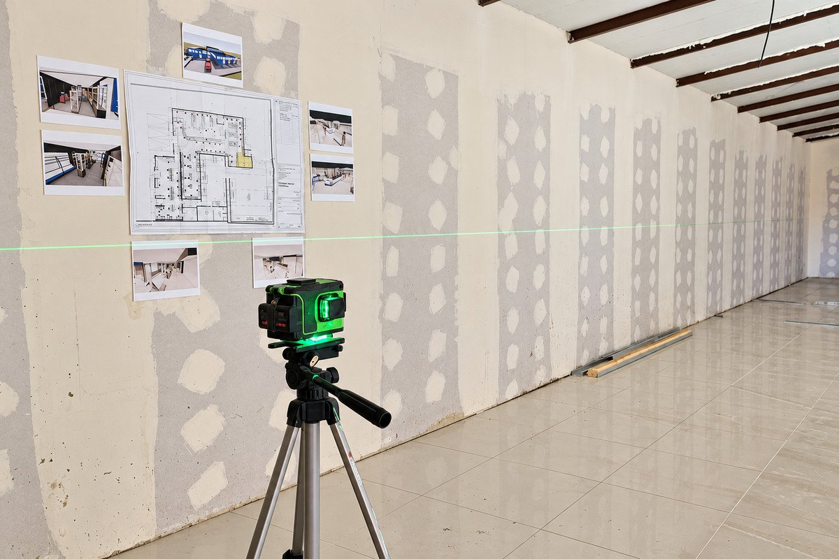 Planos en la pared y nivel láser durante la supervisión de obra